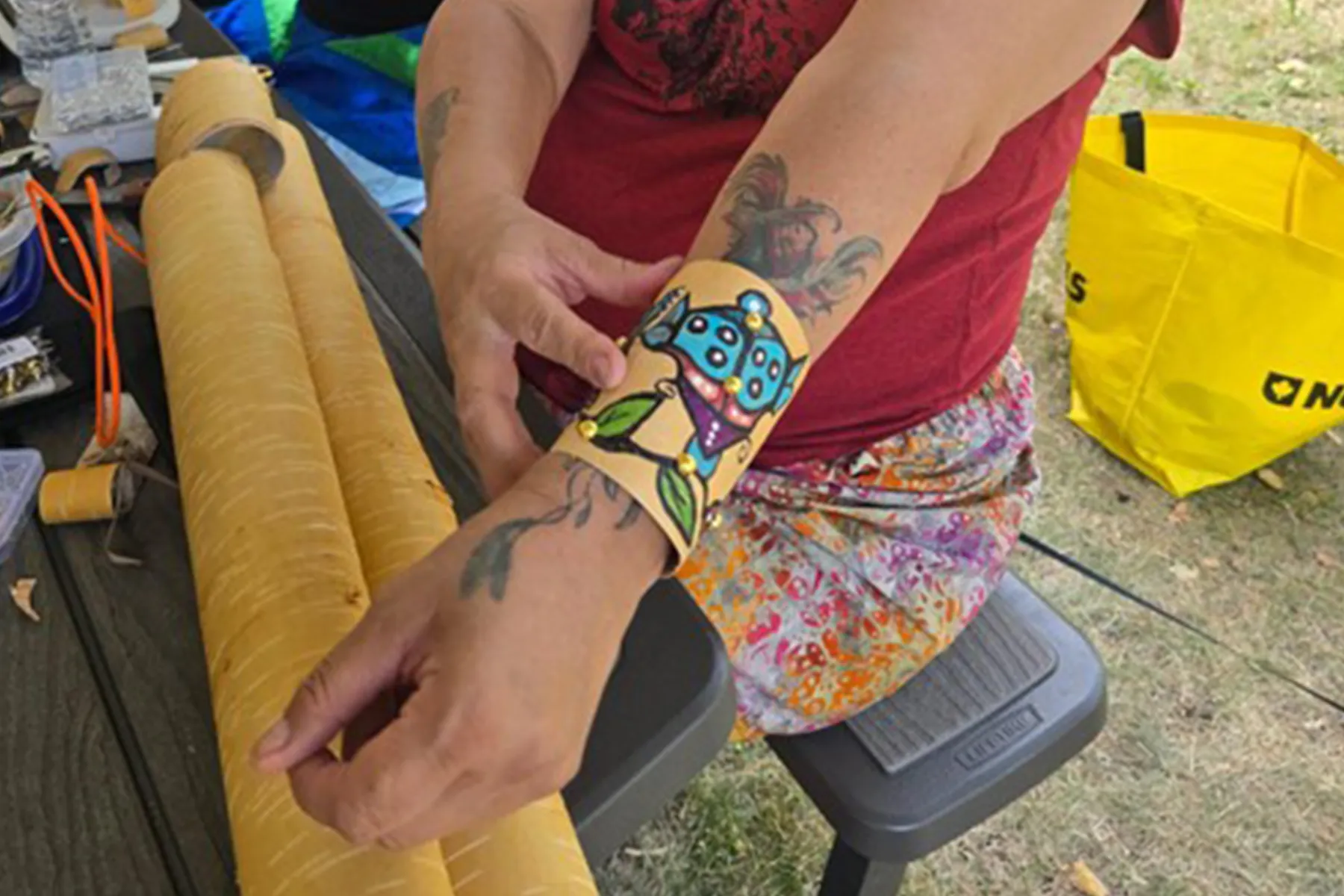 Person wearing a colourful painted and beaded bracelet, adjusting it on their wrist outdoors